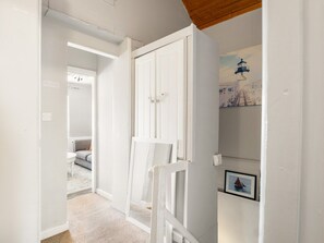 A hallway with a white door, a white chair, and a framed picture on the wall.