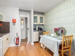 A compact kitchen with a microwave, coffee maker, and a dining area with a table set for two.
