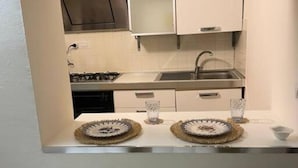 Une cuisine avec des armoires blanches, un évier en acier inoxydable et deux assiettes décoratives posées sur le comptoir.