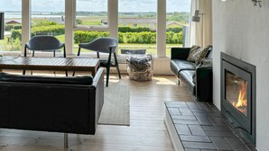 A modern living room with a fireplace, a sofa, a coffee table, and two chairs. - 3 bedroom stunning home in øster assels (Øster Assels)