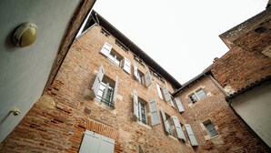 A narrow alleyway with a brick building featuring multiple windows and a door.