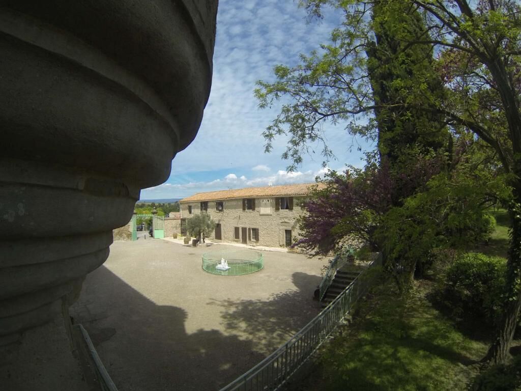 A courtyard with a fountain, surrounded by stone buildings and trees.