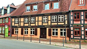 A traditional half-timbered building with a red-tiled roof, multiple windows, and a green door. - Ferienwohnung Kogge im Zentrum von Röbel (Röbel)