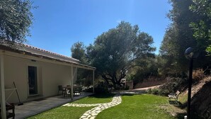 A stone pathway leading to a covered patio area with outdoor furniture. - Agreen Country House Juniper (Sardegna)