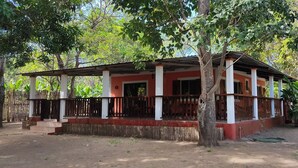 A single-story building with a porch, surrounded by trees.