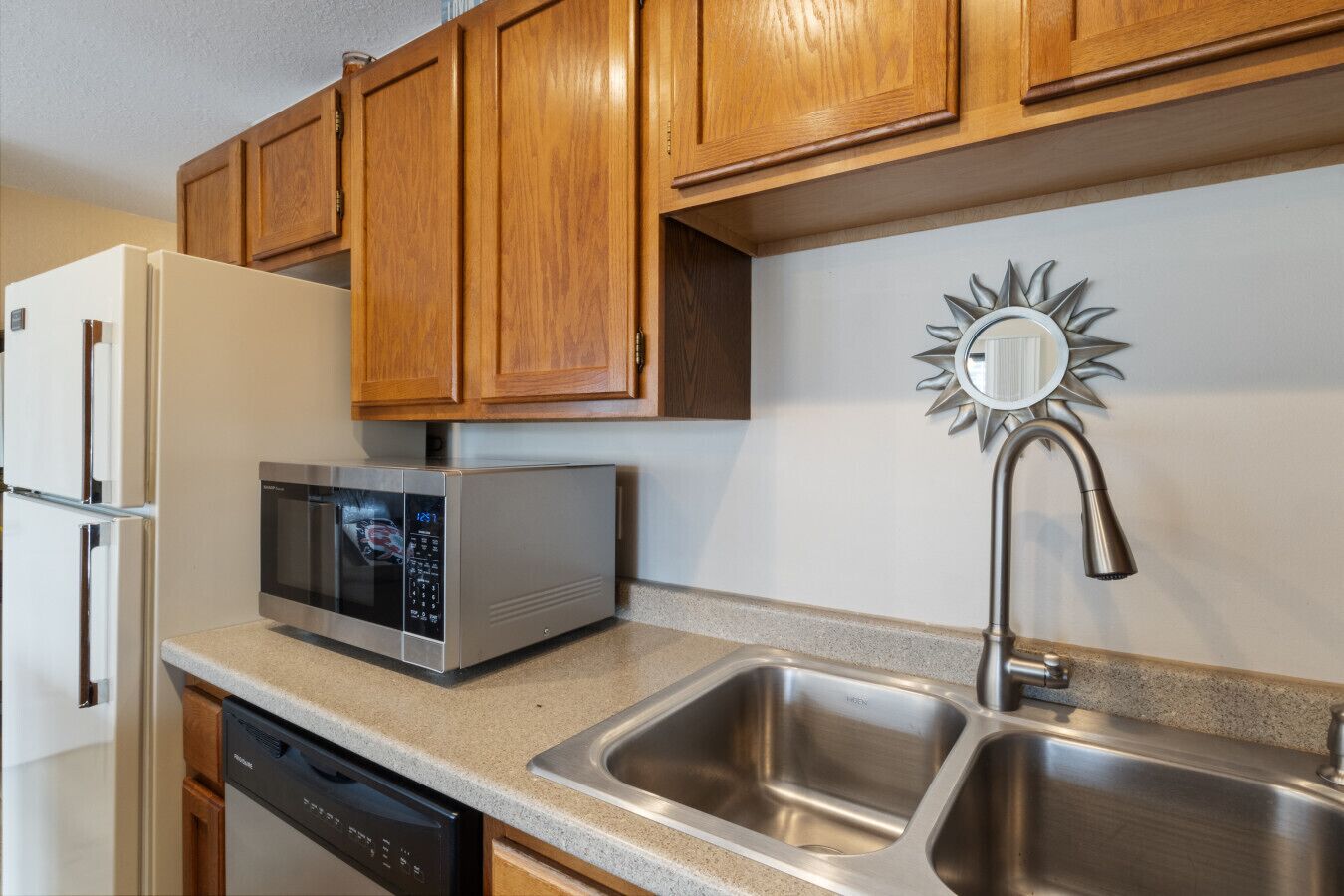 A kitchen with wooden cabinets, a stainless steel sink, a microwave, and a dishwasher.