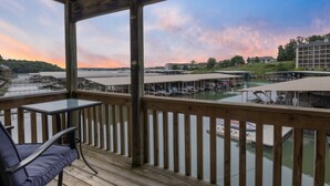 A wooden deck with a view of a marina and buildings in the background. - Reel Relaxin - Waterfront Pool, Indoor Pool & Hot Tub! (Village of Four Seasons)