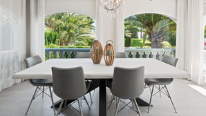 A dining area with a white table, grey chairs, and a chandelier.