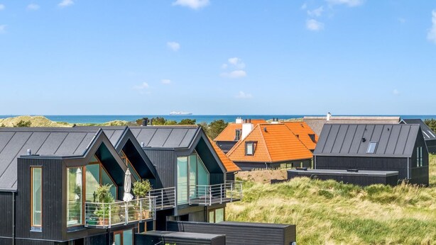 Ein modernes Gebäude an der Küste mit mehreren Etagen, großen Fenstern und Blick auf das Meer.