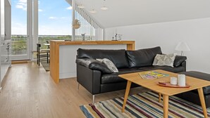 Ein modernes Wohnzimmer mit einem schwarzen Ledersofa, einem Holztisch und einem Streifen Teppich.