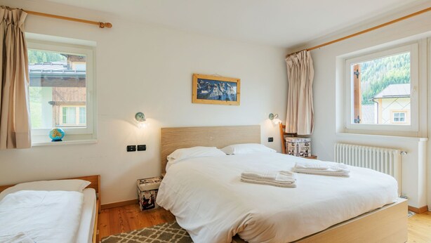 A bedroom with a wooden bed, a small bedside table, a globe, and a painting on the wall.