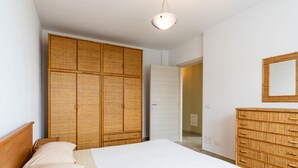 Une chambre à coucher avec un lit en bois, une grande armoire, une commode et un miroir au mur.