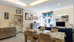 A modern living room with a dining area, a TV, and a large window with curtains. - La dimora del pontile by Interhome (Ceriale)