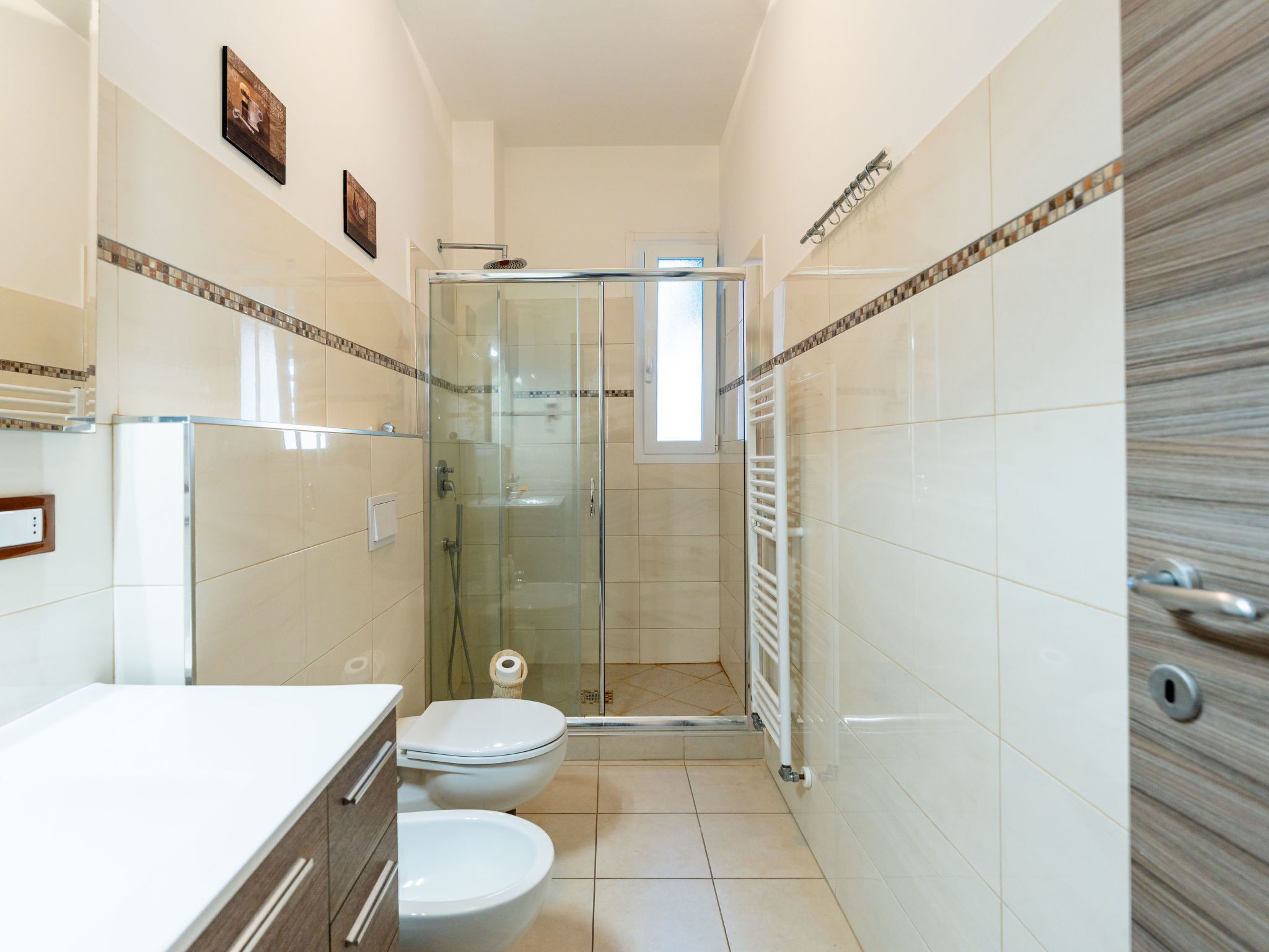 Un baño moderno con ducha de vidrio, inodoro blanco y tocador con espejo.