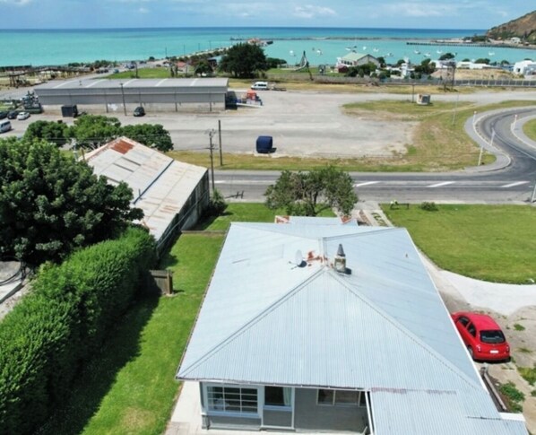 A residential area with a house featuring a metal roof, a garage, and a view of the ocean. - Big space in a great location (Oamaru)