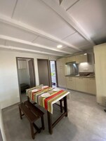 Un comedor con una mesa preparada para cuatro, un banco y vista a la cocina.