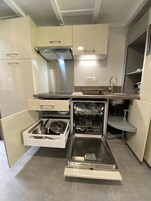 Una cocina compacta equipada con lavavajillas, un lavaplatos y una estufa.