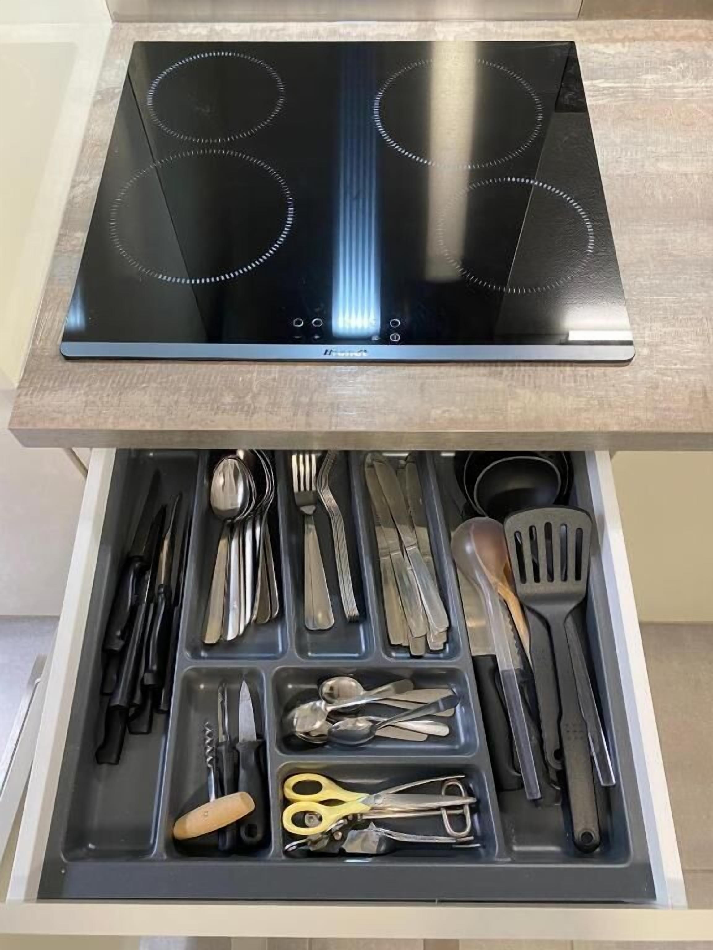Un cajón con utensilios de cocina y una hornilla.