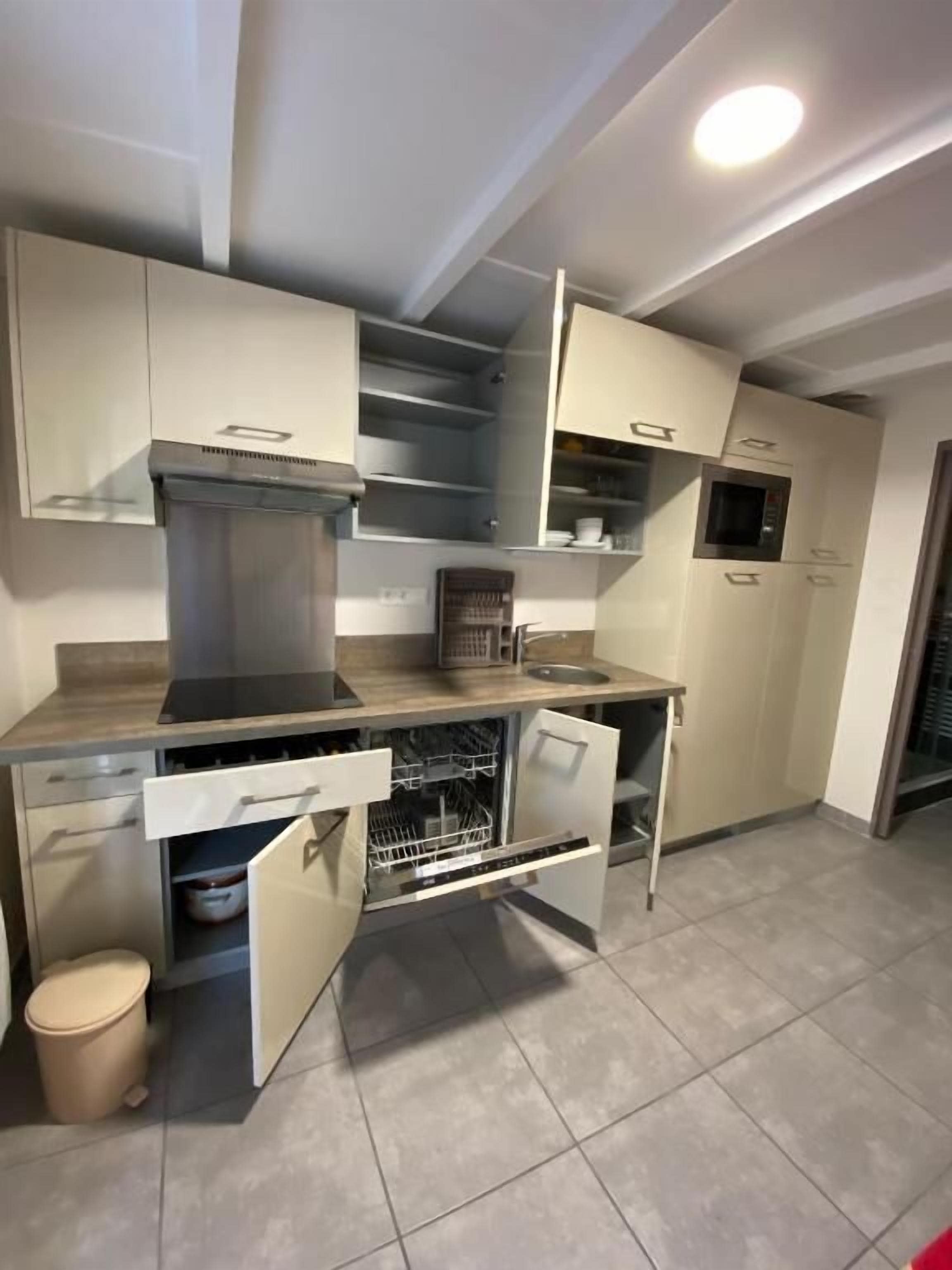 Een praktische keuken met een geïntegreerde vaatwasser, magnetron en een klein oven.