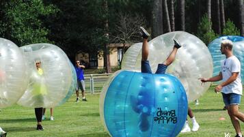 People inside large transparent inflatable balls on a grassy field.