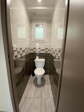 Ein schmales Badezimmer mit Toilette, Bidet und kleinem Fenster.