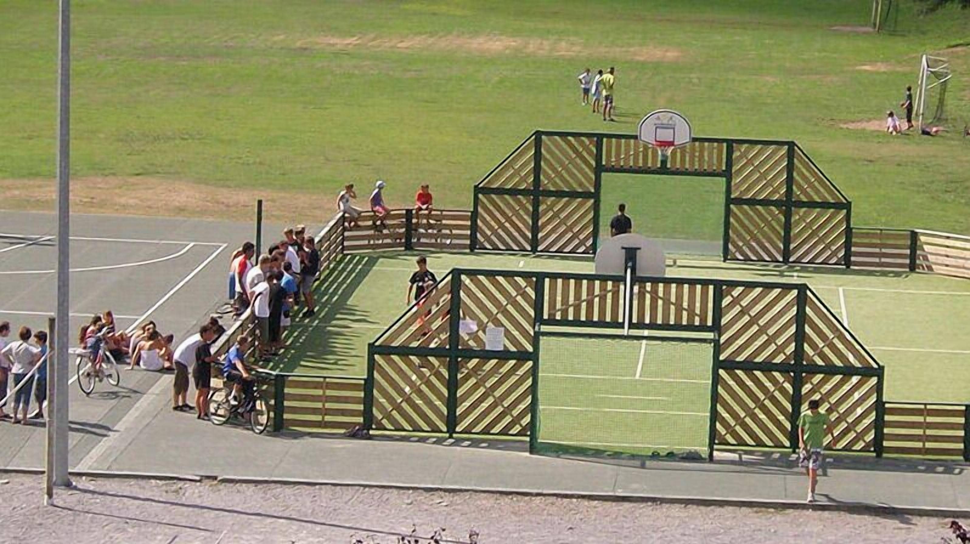Un terrain de basket-ball entouré d’une clôture en bois et équipé d’un panier de basket.