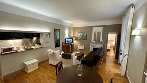 Ein modernes Wohnzimmer mit Flachbildfernseher, Kamin, Esstisch und einer gemütlichen Sitzecke.