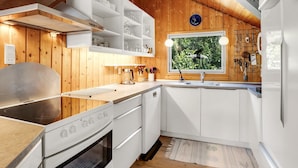 A modern kitchen with white cabinetry, a stainless steel stove, and a window with a view of greenery.