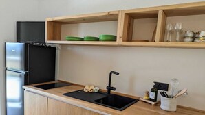 Una cocina moderna con un refrigerador negro, un lavamanos y armarios de madera.