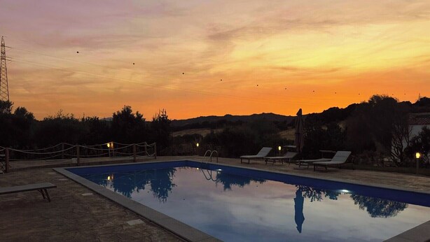 Una piscina con sillas de descanso y vistas al atardecer.