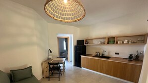 Un espacio habitable compacto con kitchenette, comedor y sofá verde.