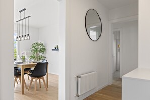 A modern dining area with a wooden table and chairs, a hanging light fixture, a potted plant, and a white radiator on the wall. - Beautifully renovated apartment with a view, in Savièse (Saint-Germain (Savièse)