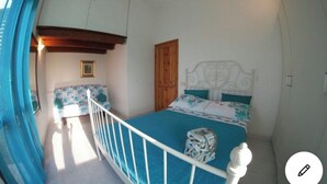 A bedroom with a bed, a wooden door, a white headboard, and a small window. - Villa Alice very close to the sea (Sardegna)