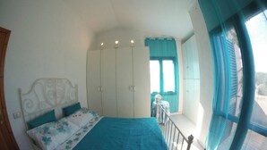 A bedroom with a bed, a wardrobe, and a window with curtains. - Villa Alice very close to the sea (Sardegna)