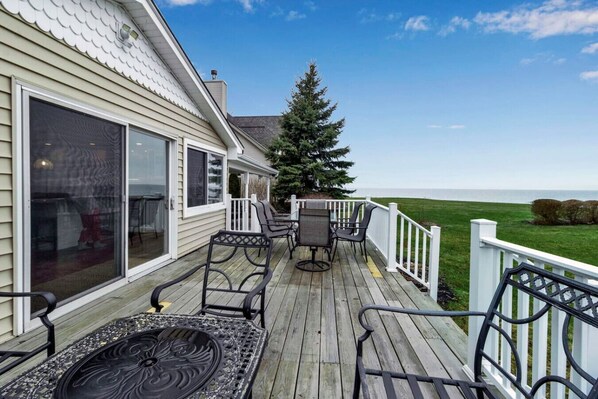 A wooden deck with outdoor furniture, a white railing, and a view of the ocean. - Lakefront 5 Bds, sleeps 8 -Blue Waters Cottage (Ransomville)