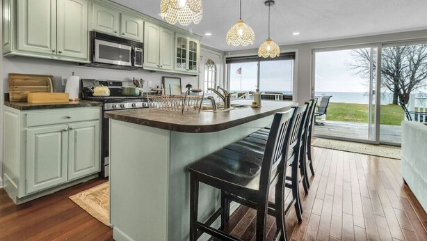 A modern kitchen with a central island, stainless steel appliances, and pendant lighting. - Lakefront 5 Bds, sleeps 8 -Blue Waters Cottage (Ransomville)