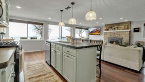 A modern kitchen with a central island, pendant lighting, and a fireplace. - Lakefront 5 Bds, sleeps 8 -Blue Waters Cottage (Ransomville)