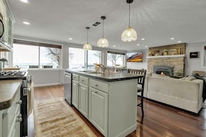 Una cocina moderna con una isla central, iluminación colgante y una chimenea.