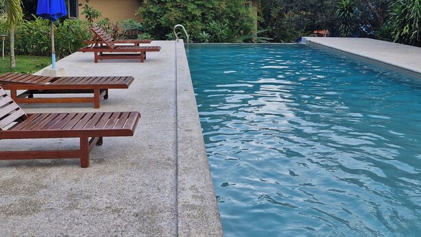 A swimming pool with lounge chairs and umbrellas.