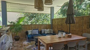 A wooden deck with a sofa, table, chairs, and a fan.