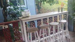 A balcony with a white railing, three wooden stools, and a potted plant.
