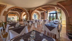 Un restaurante con varias mesas, arcos de ladrillo y vistas al exterior.