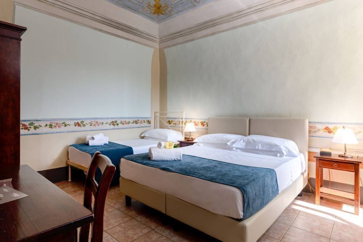 Ein Hotelzimmer mit zwei Einzelbetten, einem Holztisch und einem Nachttisch mit einer Lampe.