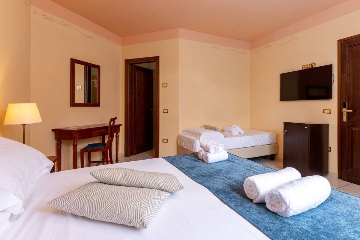 Ein Hotelzimmer mit Bett, Schreibtisch, Stuhl, Fernseher und Kleiderschrank.