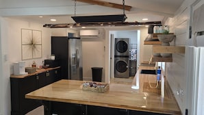 A modern kitchen with a central island, built-in appliances, and a rustic ceiling.