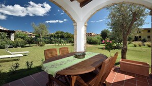 An outdoor patio with a table and chairs, surrounded by a garden and a view of the neighborhood. - Villa Menhir! (Lotzorai)