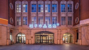 A hotel with a classic architectural style, featuring arched windows and a central entrance with glass doors.