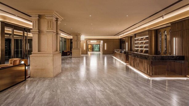 A spacious lobby with a marble floor, a reception desk, and a column.