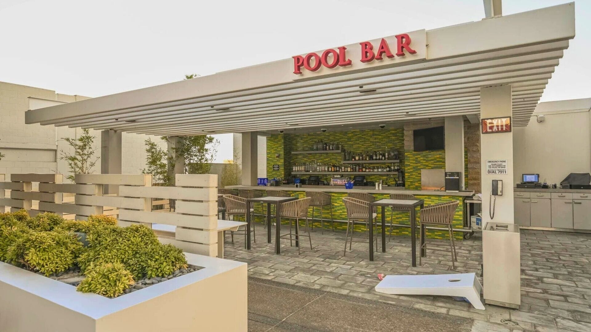 A pool bar with outdoor seating and a counter displaying various bottles.