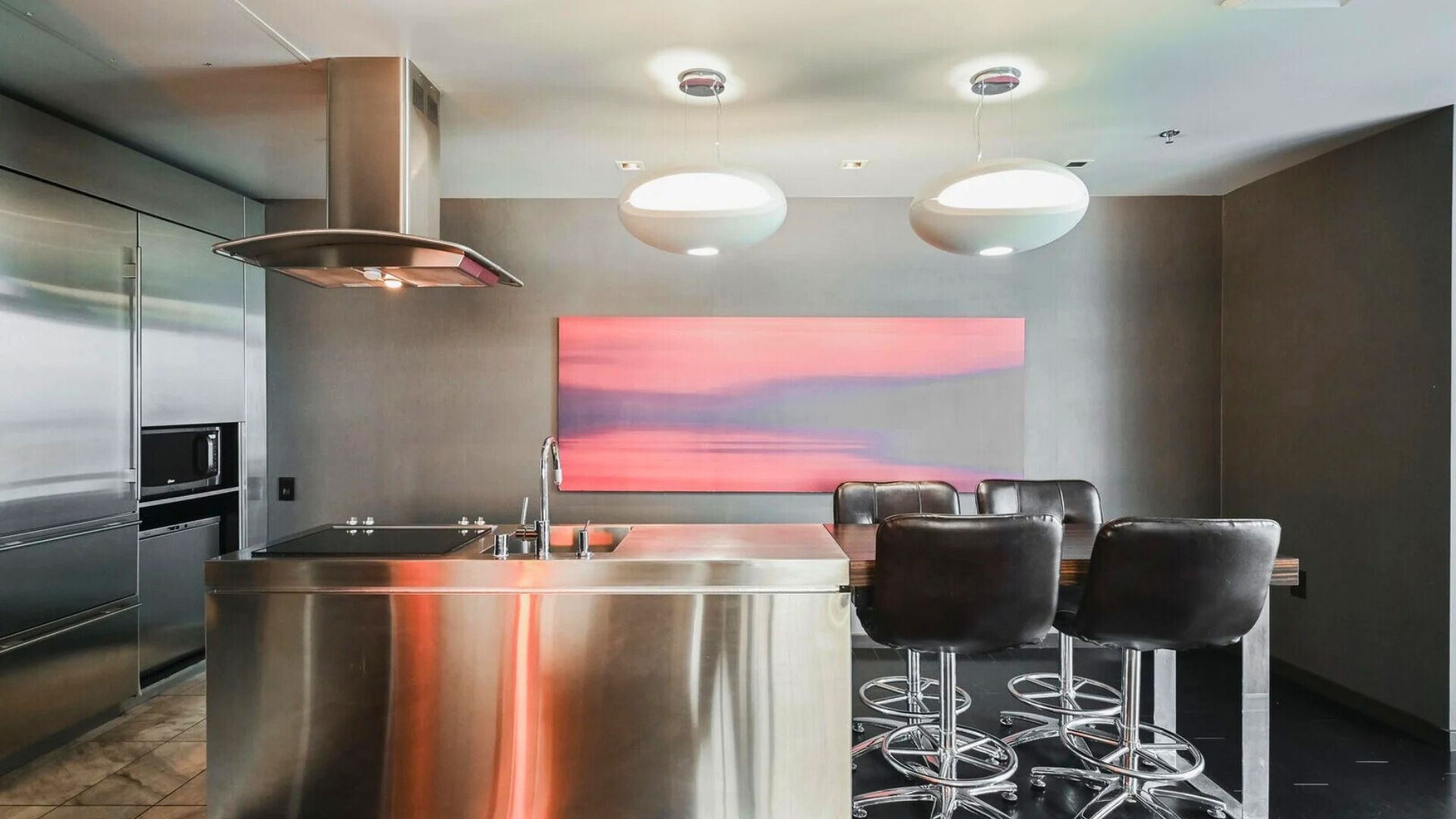 A modern kitchen with a central island, stainless steel appliances, and a bar area with stools.